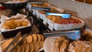 Un buffet proposant une variété de produits de boulangerie, notamment du pain, des viennoiseries et des biscuits.