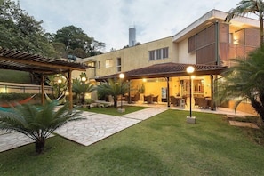 Ein modernes Haus mit Terrasse, Sitzgelegenheiten im Freien und einem Pool.