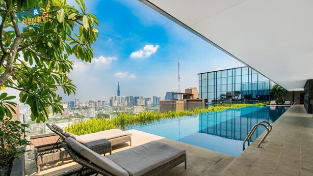 Une piscine à débordement sur le toit, dotée de chaises longues, offrant une vue sur le panorama urbain et avec un bâtiment moderne en arrière-plan.