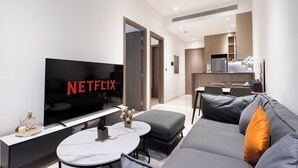 Un salon moderne avec un téléviseur à écran plat, un canapé, une table basse et un coin repas à l’arrière-plan.