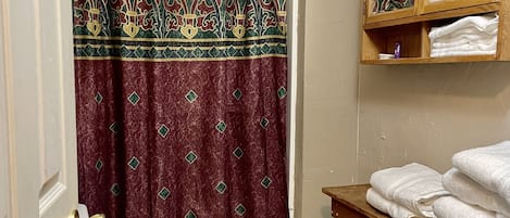 A bathroom with a toilet, a sink, a wooden vanity, a mirror, and a shower curtain.