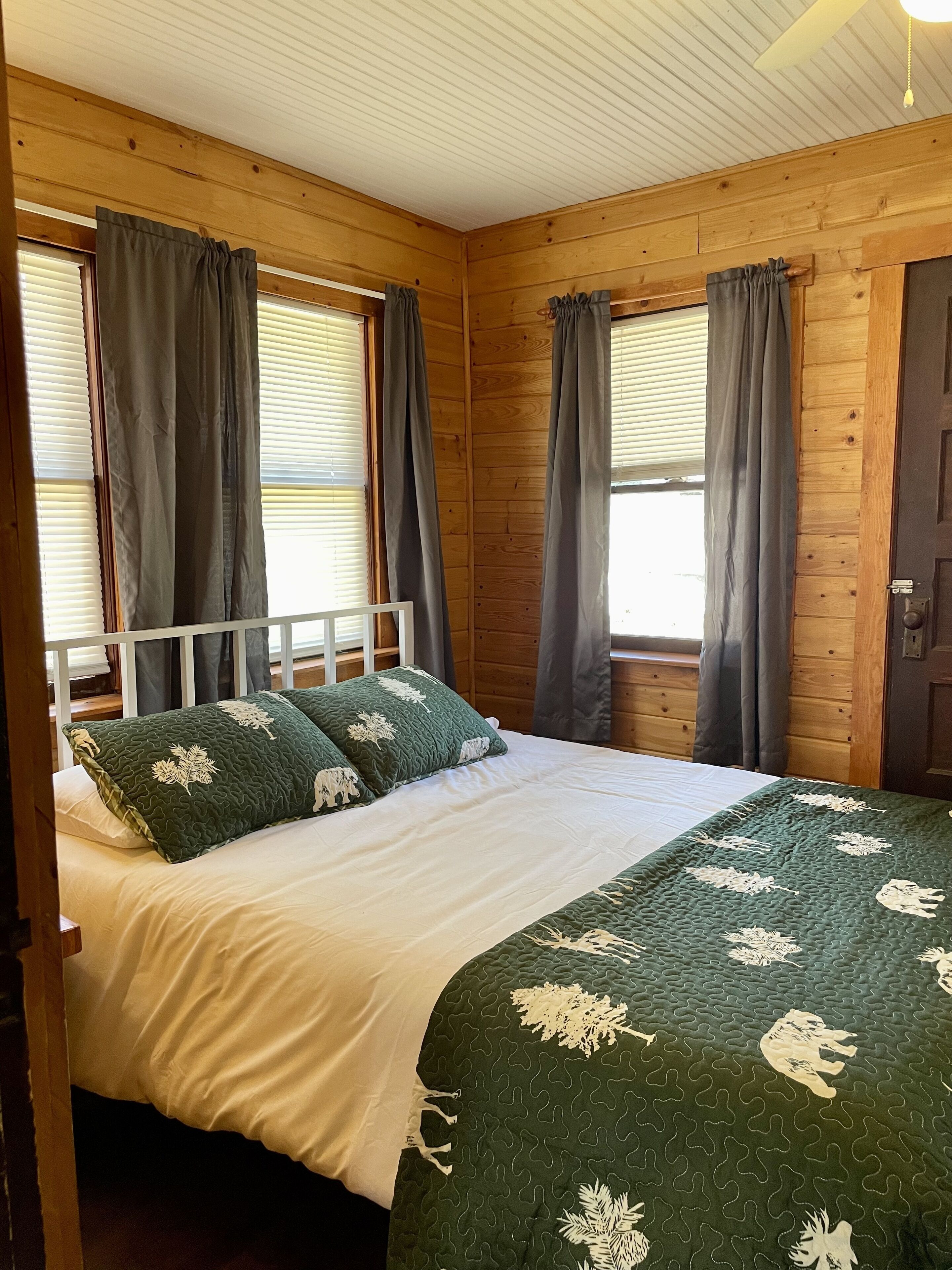 Ein Zimmer mit Holzwänden, einem Bett, Vorhängen und einer Tür.