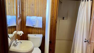 A wooden-paneled bathroom with a sink, toilet, and shower.