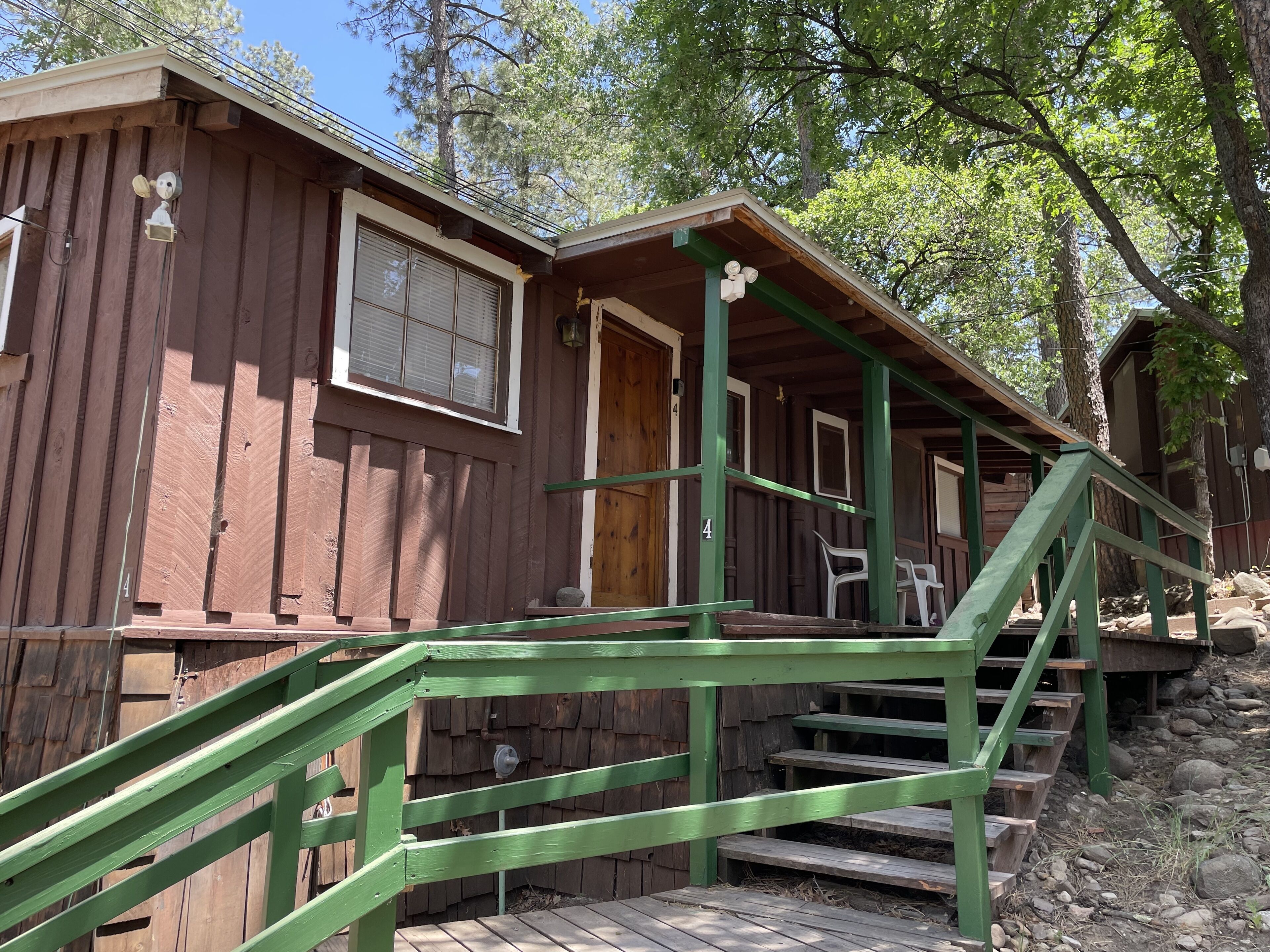 A wooden cabin with a porch, a staircase, and a window.