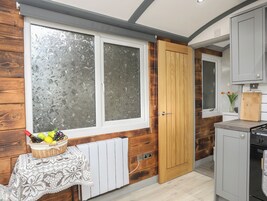 Una cocina con paneles de madera, un radiador blanco, una puerta de madera y una pequeña mesa con una cesta de fruta.