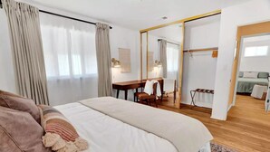 Un dormitorio moderno con una cama grande, un escritorio y un espejo.