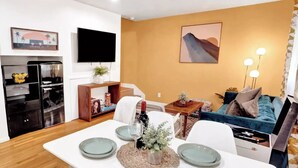 Una sala de estar moderna con comedor, televisor de pantalla plana y sofá.
