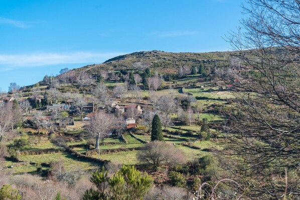 A rural landscape with scattered houses on a hillside, surrounded by trees and open fields. - 'Casa do Castanheiro | Nature | Mountain | Trails | Branda da Aveleira (Melgaço)