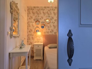 A bedroom with a bed, a bedside table, a lamp, and a wall with circular mirrors.
