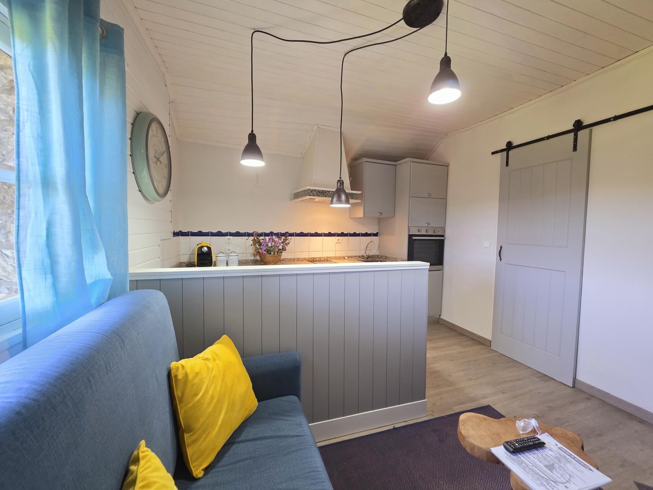 A compact living space with a sofa, a small kitchen area, and a dining table.