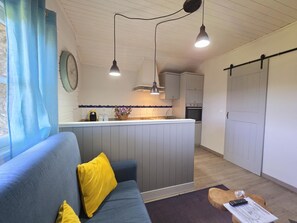 A compact living space with a sofa, a small kitchen area, and a dining table.