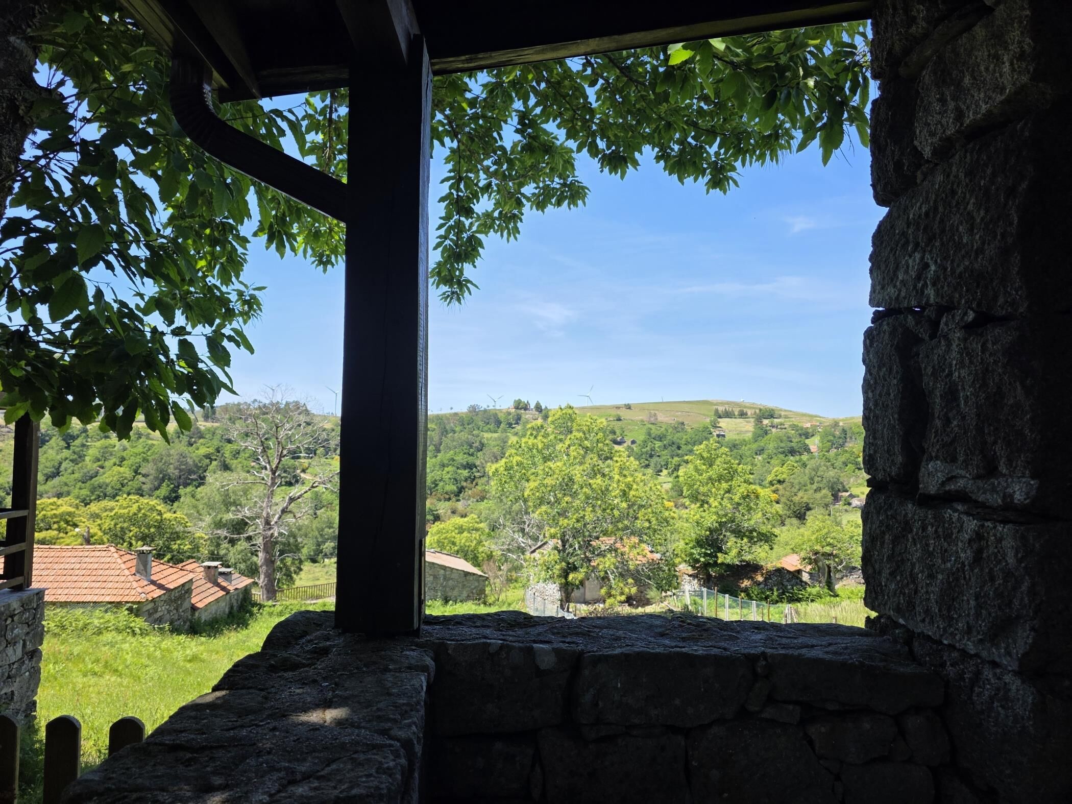 A stone structure with a view of a green landscape and hills.