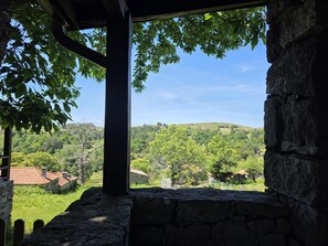 A stone structure with a view of a green landscape and hills.