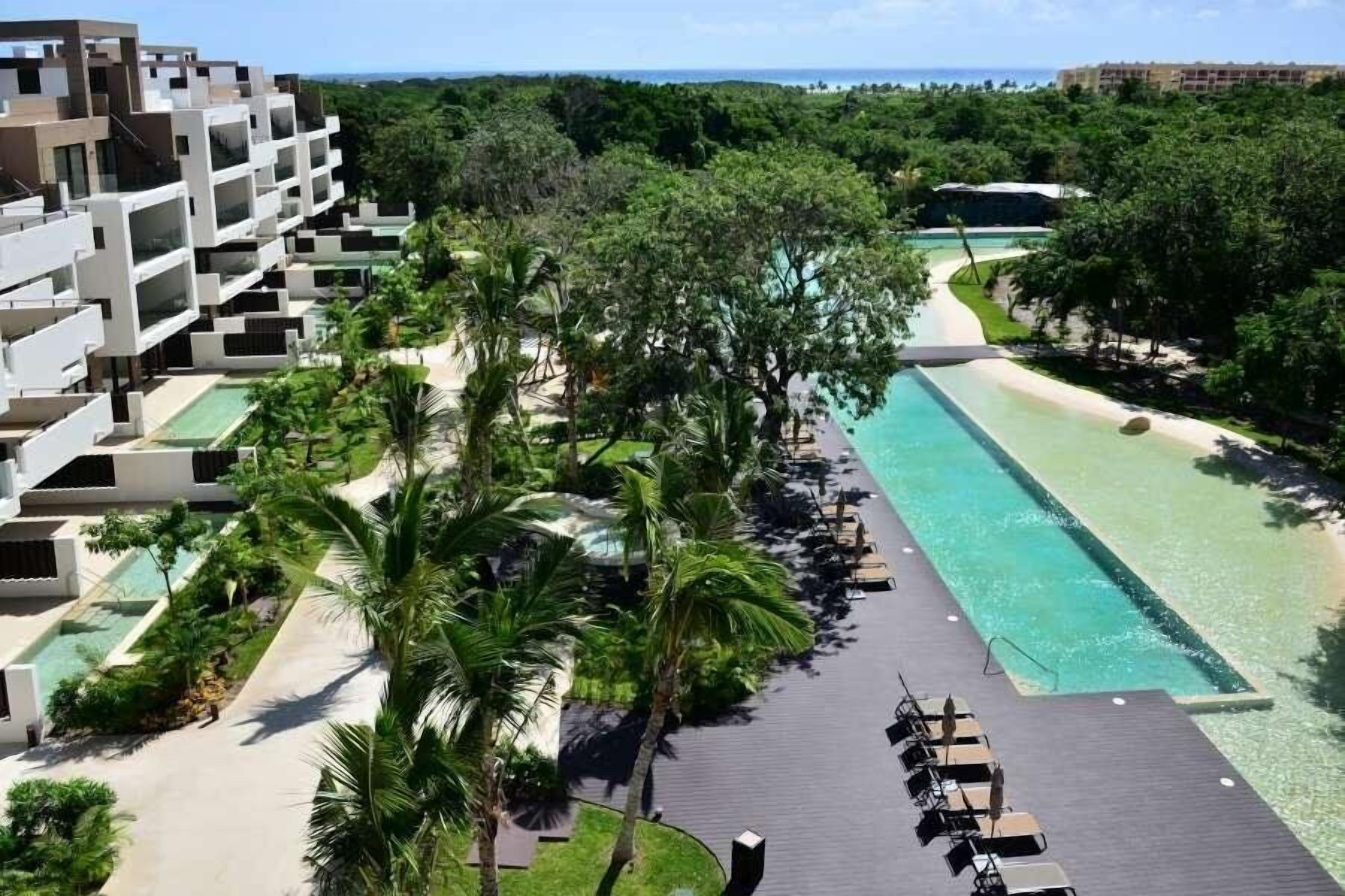 A resort with a swimming pool, palm trees, and a view of the ocean.