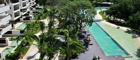 A resort with a swimming pool, palm trees, and a view of the ocean.