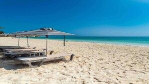 A beach with sun loungers and umbrellas, a clear blue sky, and turquoise water. - Playa del Carmen (Playa del Carmen)