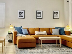 Un salon avec un canapé marron, une table basse blanche et trois tableaux encadrés accrochés au mur.