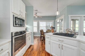 A kitchen with white cabinetry, a built-in microwave, an oven, and a large island with a kettle.