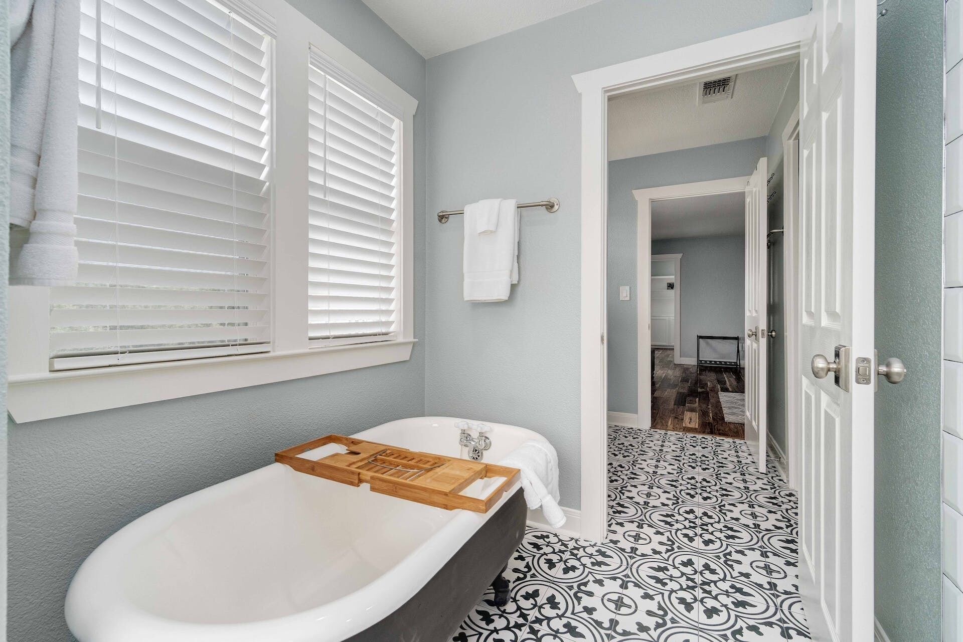 A bathroom with a freestanding bathtub, white towel rack, and patterned floor tiles.