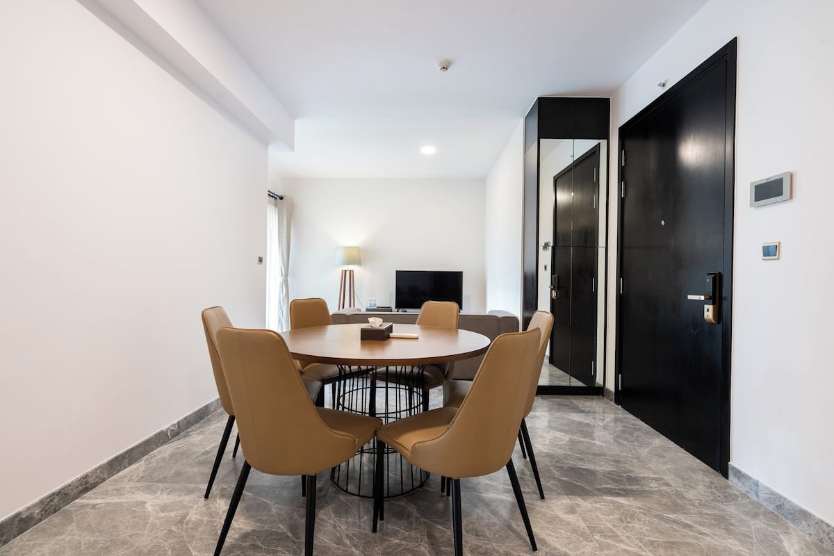 A modern dining area with a round table and six chairs, a television, and a black door.