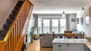 A modern kitchen with wooden flooring, a built-in island, and a staircase with wooden railings. - 2 bedroom accommodation in Haverigg (Haverigg)