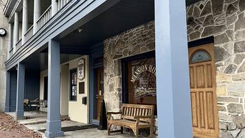 A building with a stone facade, a wooden bench, and a sign reading "Mansion House Tavern."