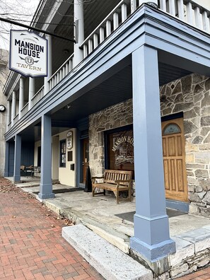 A building with a stone facade, a wooden bench, and a sign reading "Mansion House Tavern."