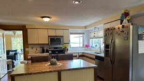A modern kitchen with a central island, stainless steel appliances, and a view to the backyard. - Spectacular sunrises,cozy vintage home on the water in Wiscasset, ME-Adults only (Wiscasset)