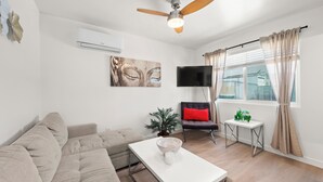 Ein modernes Wohnzimmer mit einer Couch, einem Couchtisch, einem Fernseher und einem Deckenventilator.