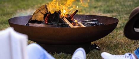 Ein Lagerfeuer mit brennenden Holzscheiten und Flammen, umgeben von Gras.
