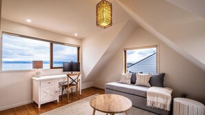 A cozy attic bedroom with a desk, chair, and a sofa with a view of the sky. - Hamptons Hideaway - Freycinet Holiday Houses (Coles Bay)