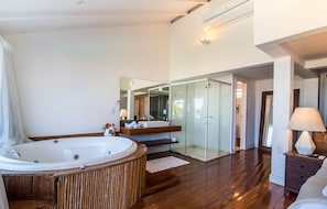 A modern bathroom with a large bathtub, a glass-enclosed shower, and a vanity with a mirror. - Greenville (Búzios)