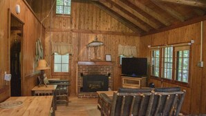 A rustic cabin interior with a wooden interior, a fireplace, a television, and a dining area. - Pine Lake Trout Club Cabin #4!!! (Chagrin Falls)