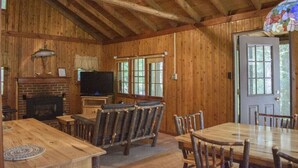 A rustic wooden interior with a fireplace, television, and dining area. - Pine Lake Trout Club Cabin #4!!! (Chagrin Falls)