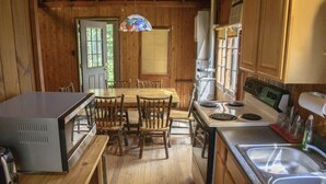 A wooden cabin kitchen with a dining table, chairs, a stove, and a sink. - Pine Lake Trout Club Cabin #4!!! (Chagrin Falls)