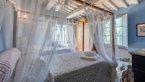 A bedroom with a canopy bed, a wooden headboard, and a window with a view of trees. - Amazing home in Città della Pieve (Città della Pieve)