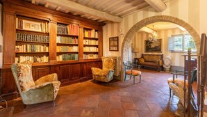 A library with bookshelves, two armchairs, a sofa, and a bust sculpture. - Amazing home in Città della Pieve (Città della Pieve)