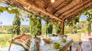 An outdoor dining area with a table set for two, surrounded by greenery and a view of the countryside. - Amazing home in Città della Pieve (Città della Pieve)