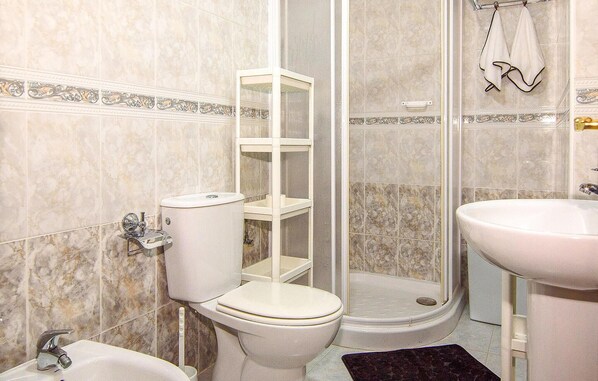 Un baño con inodoro, lavamanos, ducha y toallero.