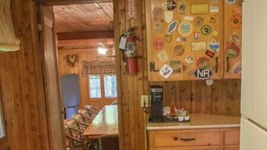 L’intérieur d’une cabane en bois comprend un coin cuisine équipé d’un poêle, d’un réfrigérateur et de meubles de rangement en bois.