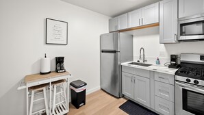 A modern kitchen with stainless steel appliances, a wooden countertop, and a small bar area. - Updated and Cozy Apartment in heart of OB!  (San Diego)
