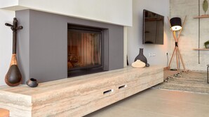 A modern living room with a built-in fireplace, a flat-screen TV mounted on the wall, and a minimalist console table with decorative items.