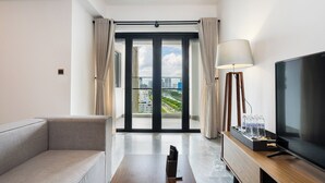 A modern hotel room with a sofa, a TV, a lamp, and a view of the city through large windows. - D1 Mension Building (Ho Chi Minh City)