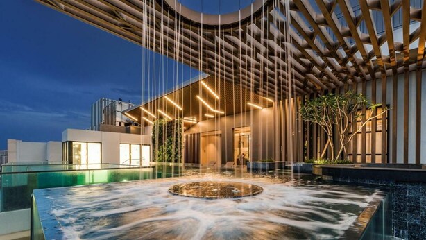 A modern spa area with a hot tub, a wooden ceiling structure, and a view of the cityscape at dusk. - D1 Mension Building (Ho Chi Minh City)