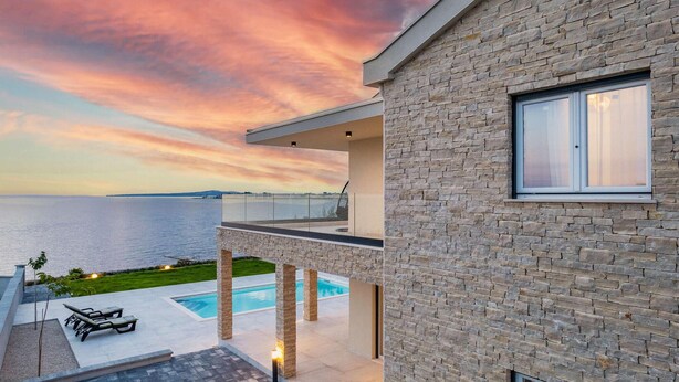 A modern house with a pool, stone facade, and a view of the sea at sunset. - Cozy home in Privlaka (Privlaka)