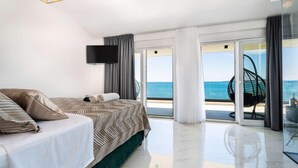 A modern hotel room with a large bed, a flat-screen TV, and a balcony with a view of the sea. - Cozy home in Privlaka (Privlaka)