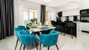 A modern dining area with a marble table, teal chairs, and a view of the sea. - Cozy home in Privlaka (Privlaka)