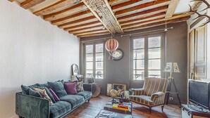 A cozy living room with a green sofa, a striped armchair, and a wooden coffee table. There are large windows with curtains, a globe, and a framed picture on the wall. - 5 bedroom beautiful home in Villeneuve-sur-Yonne (Villeneuve-sur-Yonne)