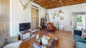 A cozy living room with a wooden ceiling, a television, a leather armchair, and a bookshelf. - 5 bedroom beautiful home in Villeneuve-sur-Yonne (Villeneuve-sur-Yonne)