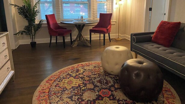 A living room with a round rug, two ottomans, a sofa, a dining table with chairs, and a potted plant. - NOLA Vibe/Oversized 1 bedroom/Entire unit (Kansas City)